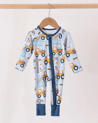 A baby long-sleeve footless romper hanging on a wooden hanger, featuring a light blue and white background with a construction vehicle print in yellow, orange, and blue, and solid navy blue trim.