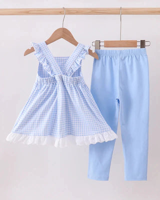 Children's blue checkered dress and leggings set on hangers against a white background