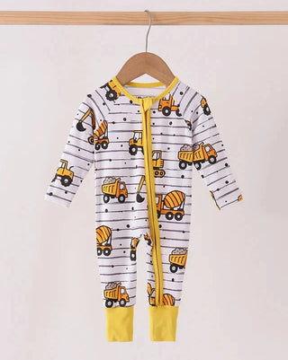 A baby long-sleeve footless one-piece romper hanging on a wooden hanger, featuring a white background with thin black horizontal stripes, a yellow zipper, and an all-over print of yellow construction vehicles including excavators, dump trucks, and a cement mixer.