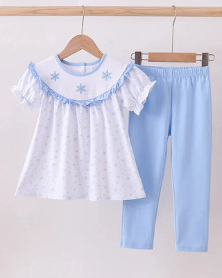 Children's outfit with white top and blue pants on a hanger against a light background