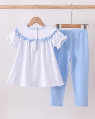 Children's outfit with white top and blue pants on a hanger against a white background
