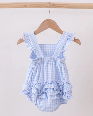 Blue checkered baby romper with ruffles on a wooden hanger against a white background