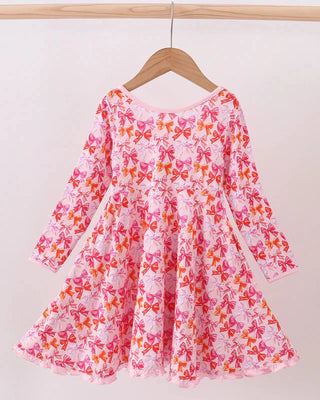 Pink dress with orange floral pattern on a hanger against a white background