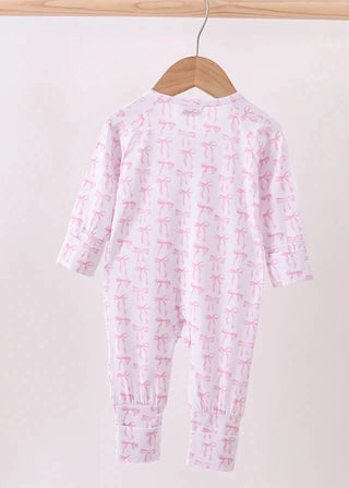 Baby onesie with pink bow pattern on a hanger against a white background