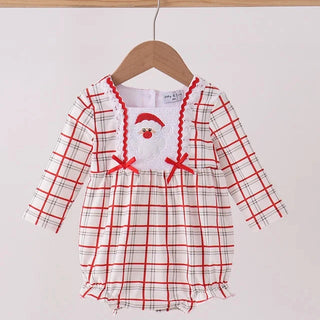 A baby long-sleeve romper with a red and black plaid pattern, featuring a white chest panel with a red Santa hat applique and red ribbon bows, hanging on a wooden hanger.