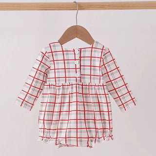 A long-sleeve baby romper in a red, white, and black plaid pattern, hanging on a wooden hanger from a light wood clothing rack against a plain off-white background.