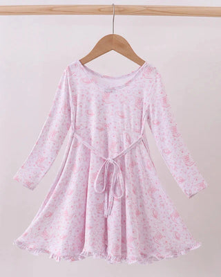 Pink floral dress on a wooden hanger against a white background