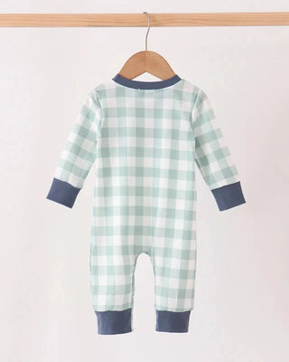 A baby long-sleeve footless romper with a light green and white gingham check pattern and navy blue trim, hanging on a wooden hanger against a plain off-white background.