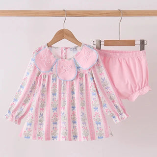 A two-piece toddler girl's outfit set hanging on wooden hangers against a plain light background. The set includes a long-sleeve pink and white floral striped blouse with a large pink Peter Pan collar, and matching pink ruffled bloomers.