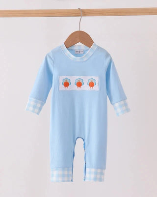 A baby long-sleeve footless romper in light blue, hanging on a wooden hanger. The romper features a white chest patch with three cartoon penguins and light blue and white gingham checkered cuffs and hem.