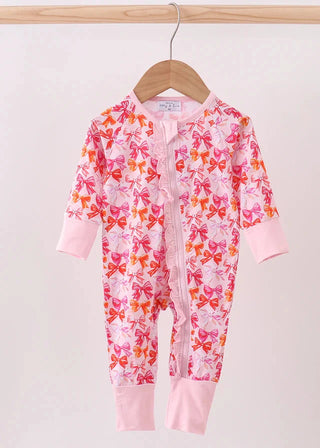Baby onesie with bow pattern on a hanger against a light pink background