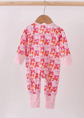 Pink baby onesie with colorful bow pattern on a hanger against a white background