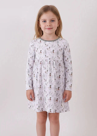 Young girl wearing a patterned dress against a plain background