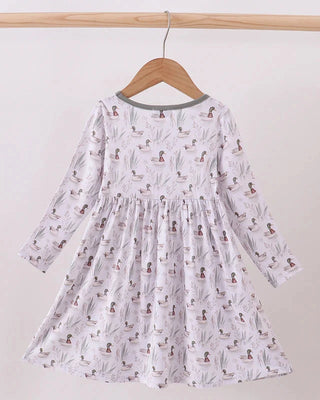 White dress with duck pattern on a wooden hanger against a white background