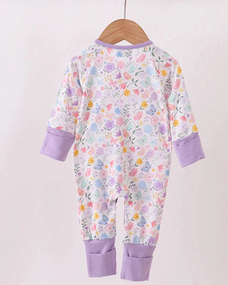 Floral-patterned baby onesie with purple accents on a wooden hanger against a white background