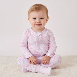 Baby wearing a pink floral onesie sitting on a white carpet.