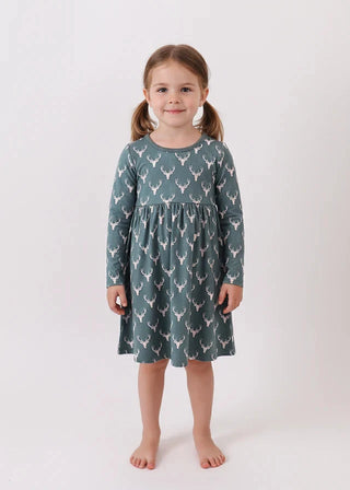 Young girl wearing a green dress with deer pattern on a white background