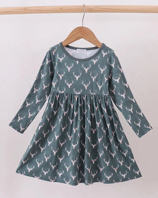 Green dress with deer pattern on a wooden hanger against a white background