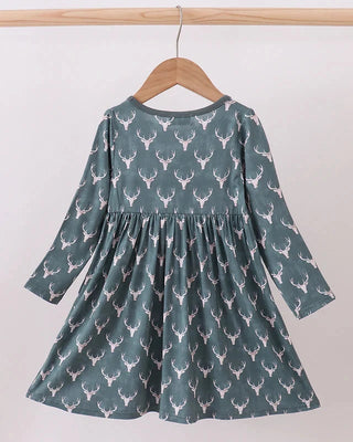 Green dress with deer pattern on a hanger against a white background
