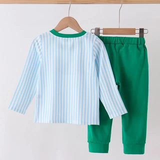 A two-piece children's outfit hanging on wooden hangers from a wooden rod. The set includes a long-sleeve top with light blue and white vertical stripes and a green collar, paired with solid green jogger pants.