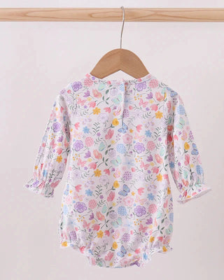 Floral-patterned baby romper on a wooden hanger against a white background