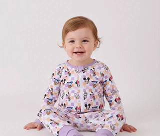 Baby wearing a colorful outfit with cartoon characters on a white background