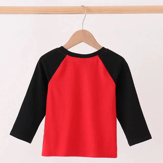 A long sleeve raglan top hanging on a wooden hanger, featuring a bright red body and black sleeves, set against a plain white background.