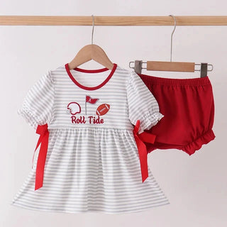 A baby girl's two-piece outfit set consisting of a white and gray striped short-sleeve dress with red trim, red ribbon side bows, and a matching red bloomers set, hanging on wooden hangers against a light pink background.