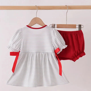 A baby girl's two-piece outfit set hanging on wooden hangers from a light wood rod. The set includes a short-sleeve dress with thin gray and white horizontal stripes, red trim at the collar, red ruffled cuffs, and red side bows, paired with solid red bloomers.
