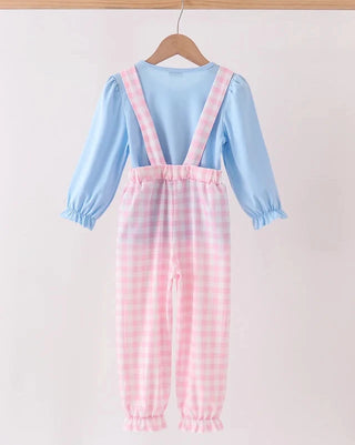 A baby girl's long-sleeve jumpsuit featuring a light blue top and pink-and-white gingham checkered overalls, hanging on a wooden hanger against a plain light background.