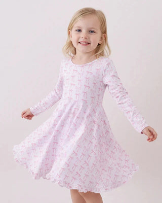 Young girl wearing a pink dress with a subtle pattern on a white background