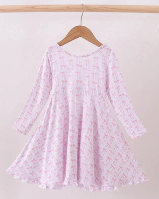 Pink dress with white floral pattern on a wooden hanger against a beige background