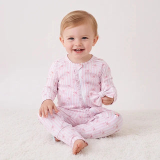 Baby wearing pink pajamas with a subtle pattern on a white background