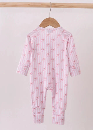 Pink baby onesie with bow pattern on a wooden hanger against a white background