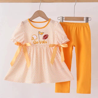 A toddler girl's two-piece outfit set hanging on wooden hangers against a light background. The set includes a short-sleeve dress with yellow polka dots, yellow trim, and yellow ribbon bows, and matching solid yellow leggings.