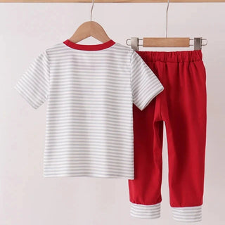 A two-piece children's outfit set hanging on wooden hangers from a wooden rod. The set includes a short-sleeve top with thin white horizontal stripes on a white background and a red collar, paired with solid red pants featuring white striped cuffs.