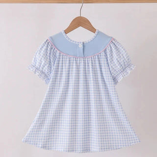 A short-sleeve dress with a light blue and white gingham pattern, featuring a solid light blue Peter Pan collar with a single button closure, hanging on a wooden hanger.