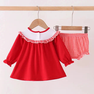 A two-piece children's outfit hanging on wooden hangers against a plain light background. The set includes a bright red long-sleeve top with a white collar and ruffled trim, paired with matching red-and-white gingham shorts.