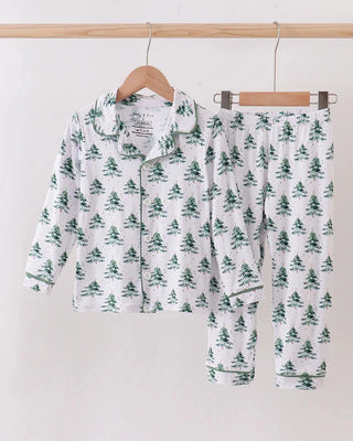 Children's pajama set with tree pattern on hangers against a white background