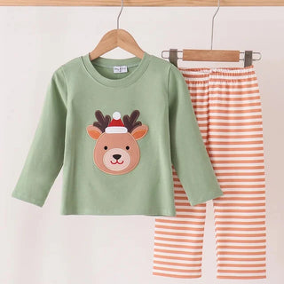 A children's two-piece outfit set hanging on a wooden hanger bar. The set includes a sage green long-sleeve top with a cartoon reindeer face wearing a Santa hat, and matching orange and white striped pants.