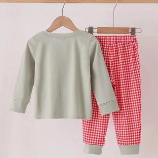 A two-piece children's outfit set hanging on wooden hangers against a plain light background. The set includes a sage green long-sleeve top and red-and-white gingham check pants with sage green cuffs.