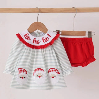 A toddler girl's Christmas outfit set consisting of a white and light green striped long-sleeve top with a red ruffled collar that says 'ho ho ho!' and three embroidered Santa faces, paired with red ruffled bloomers, hanging on wooden hangers.