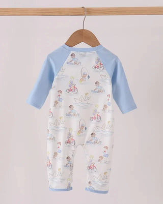 A baby long-sleeve romper hanging on a wooden hanger, featuring light blue raglan sleeves and a white body with a colorful cartoon print of children riding bicycles and sailing.