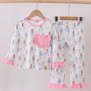 Children's pajama set with pink ruffles on a wooden hanger against a light gray background
