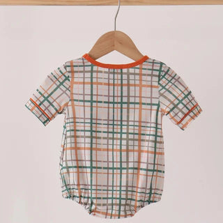 A baby short-sleeve romper with a green, orange, and white plaid pattern, hanging on a wooden hanger from a light wood rod against a plain off-white background.