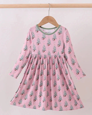 Pink dress with tree pattern on a hanger against a light background