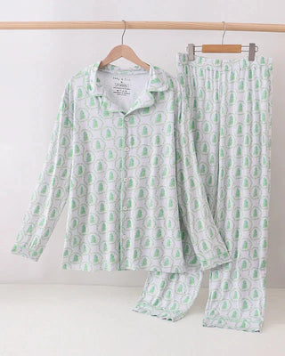 Green and white pajama set on hangers against a white background