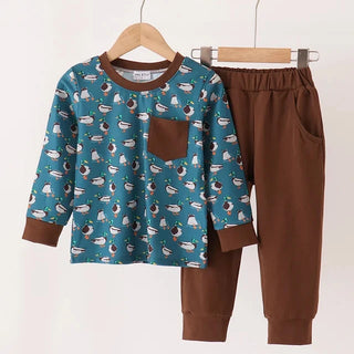 A two-piece children's jogger set hanging on wooden hangers against a plain white background. The set includes a long-sleeve top in teal blue with a white and brown patterned print, a solid brown chest pocket, and matching solid brown cuffs and hem, paired with solid brown jogger pants.