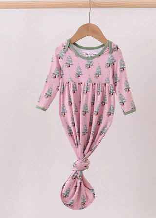 Pink baby outfit with tree pattern on a hanger against a light pink background