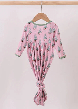 Pink baby romper with tree pattern on a wooden hanger against a white background